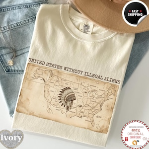 May include: An ivory short-sleeve t-shirt featuring a vintage-style map of the United States with the text UNITED STATES WITHOUT ILLEGAL ALIENS printed above. The map includes various tribal names and a central illustration of a feathered headdress.