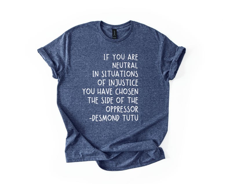 May include: A navy blue t-shirt with white text. The text reads: "IF YOU ARE NEUTRAL IN SITUATIONS OF INJUSTICE YOU HAVE CHOSEN THE SIDE OF THE OPPRESSOR -DESMOND TUTU."