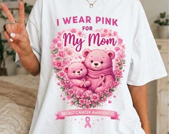 Op de afbeelding: Een wit t-shirt met een afbeelding van twee roze teddyberen omringd door een hartvormige krans van roze bloemen. De tekst luidt I WEAR PINK FOR My Mom en BREAST CANCER AWARENESS, vergezeld van een roze lintsymbool.