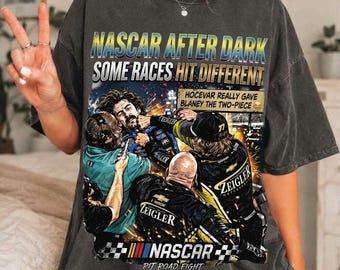 Op de afbeelding: Een antracietgrijs t-shirt met een grafische print met de tekst NASCAR AFTER DARK SOME RACES HIT DIFFERENT. Het ontwerp toont een gevecht in de pitstraat met de tekst HOCEVAR REALLY GAVE BLANEY THE TWO-PIECE en NASCAR PIT ROAD FIGHT.