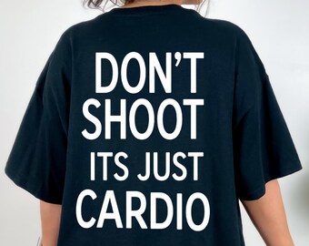Op de afbeelding: Een zwart t-shirt met korte mouwen en witte tekst op de achterkant die luidt: DON'T SHOOT ITS JUST CARDIO. Het shirt heeft een ronde hals en een losse, ontspannen pasvorm, wat zorgt voor een eenvoudig ontwerp voor dagelijks gebruik.
