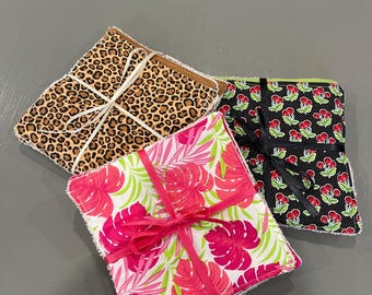 May include: Three sets of reusable makeup remover pads, tied with white ribbon. The pads are made of soft fabric and feature different patterns: leopard print, tropical leaves, and black with red cherries.