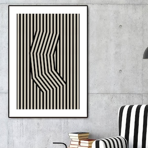 Könnte beinhalten: Ein schwarz-weiß gestreifter Sessel mit einer schwarzen Lampe und einem gerahmten schwarz-weißen geometrischen Druck an der Wand dahinter.