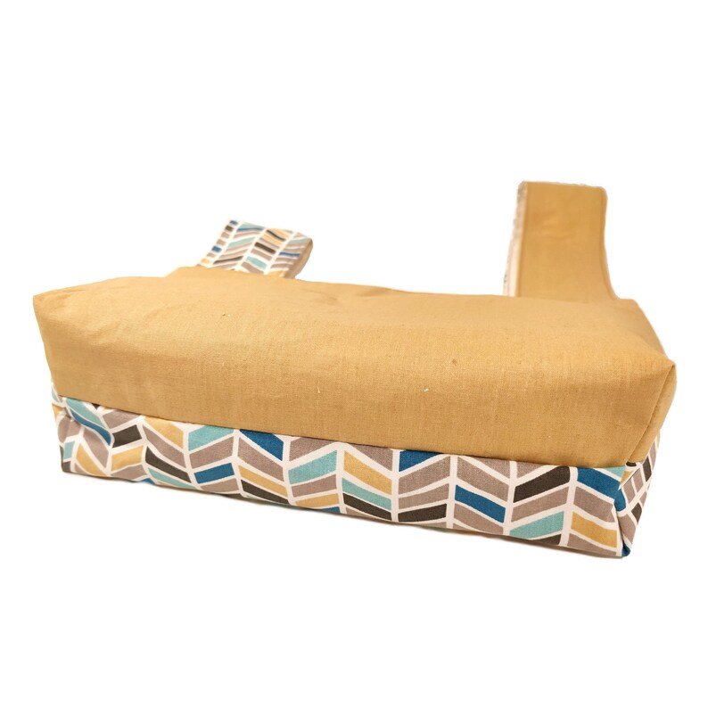 May include: A yellow tote bag with a geometric pattern in shades of blue, brown, and white. The bag has two straps.