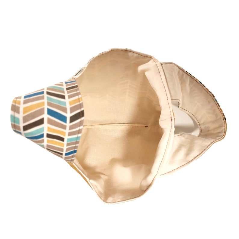 May include: A beige tote bag with a chevron pattern in shades of brown, blue, and yellow. The bag is open and the inside is visible.