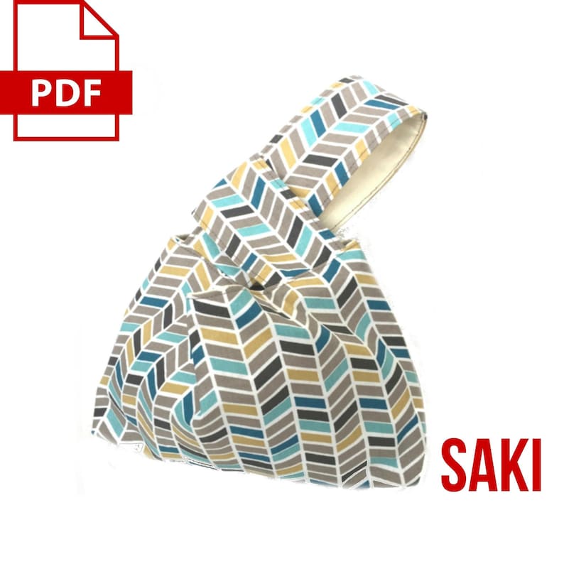 May include: A blue, gray, and yellow chevron patterned tote bag with a single handle. The bag is folded and the text "SAKI" is printed in red on the right side of the image.