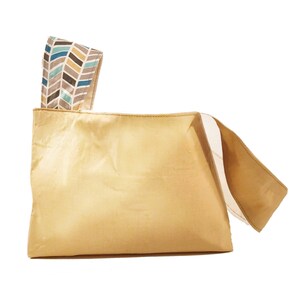 May include: A light beige fabric tote bag with a geometric patterned fabric handle. The handle is folded over and the bag is laying flat.