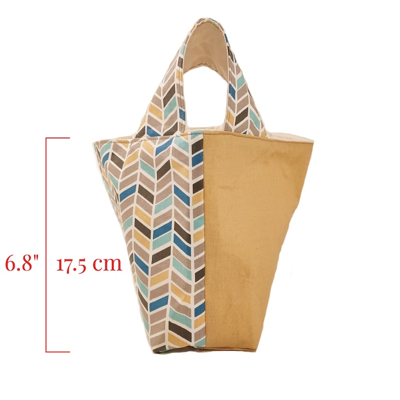 May include: A beige and blue chevron patterned tote bag with a solid beige side panel. The bag has a 6.8 inch height and a 17.5 cm width.