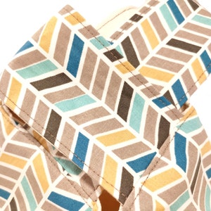 May include: A close-up of a fabric with a chevron pattern in shades of brown, blue, yellow, and white. The fabric has a subtle texture and is sewn with a straight stitch.