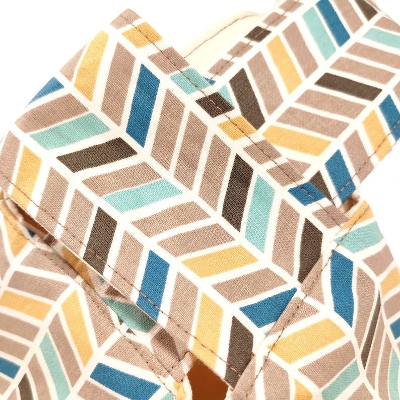 May include: A close-up of a fabric with a chevron pattern in shades of brown, blue, yellow, and white. The fabric has a subtle texture and is sewn with a straight stitch.