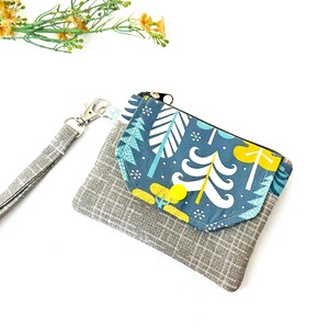 Cartera pequeña gris con cierre de cremallera y cordón, ideal para regalar por menos de 15 dólares.