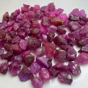 May include: A white ceramic mug with a black handle and the text "But First, Coffee" in a bold, black font. The mug is set against a neutral background, highlighting its simple design.