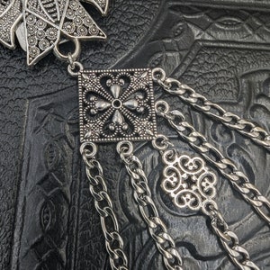 May include: Silver pendant with a square filigree design and a chain with a smaller filigree charm. The pendant is attached to a chain with multiple strands.