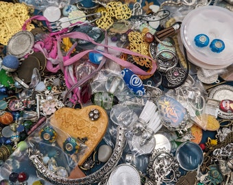 May include: A collection of colorful and metallic jewelry findings, including beads, charms, pendants, and clasps. The findings are arranged on a table and include a variety of shapes, sizes, and materials.