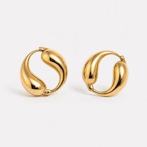 May include: A pair of gold-coloured hoop earrings. Each earring features a smooth, teardrop-shaped design with a polished finish. The earrings are set against a white background, emphasising their reflective surface and elegant form.