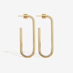 May include: A pair of gold-colored, U-shaped hoop earrings. Each earring features a post and a rounded top, with a long, straight vertical bar that curves at the bottom. The earrings are displayed against a white background.