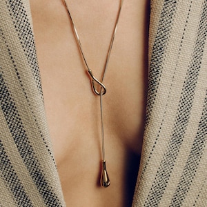 Adjustable knot layered necklace with a Y-lariat drop chain and a gold or silver toggle pendant. Versatile design can be worn long, as a choker, or layered with other necklaces. A minimalist long drop chain necklace perfect for everyday wear, Thanksgiving gatherings, Christmas parties, New Year celebrations, and holiday gifting.