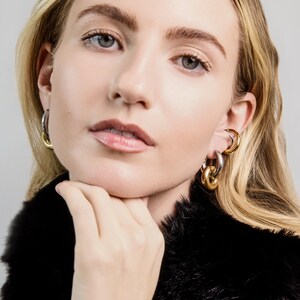 old and silver mixed metal link earrings worn on ear, bold chunky hoop earrings with polished finish.