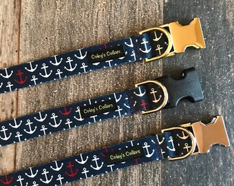 May include: Three dog collars with a navy blue background and white anchors. The collars have gold and silver buckles and a red accent. The collars are labeled "Coley's Collars".
