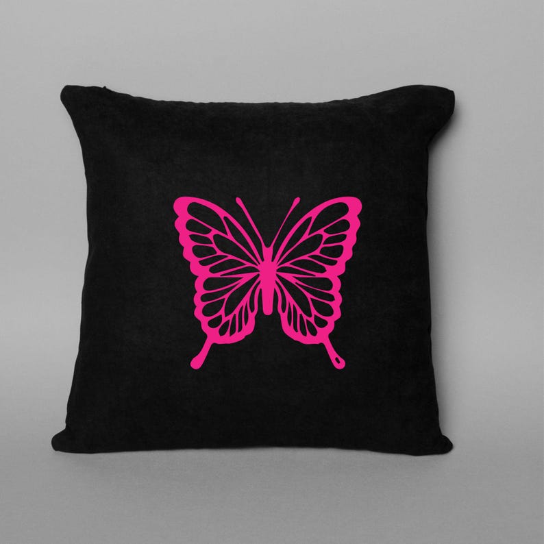 May include: A black square throw pillow featuring a bright pink butterfly design. The butterfly is centered on the pillow and has detailed wing patterns. The pillow is a solid black color.
