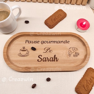 Peut inclure: Un plateau ovale en bambou clair avec l'inscription "Pause gourmande De Sarah". Il est orné d'une tasse à café, d'un croissant et de grains de café gravés. Une tasse blanche, des biscuits et une bougie sont également visibles.