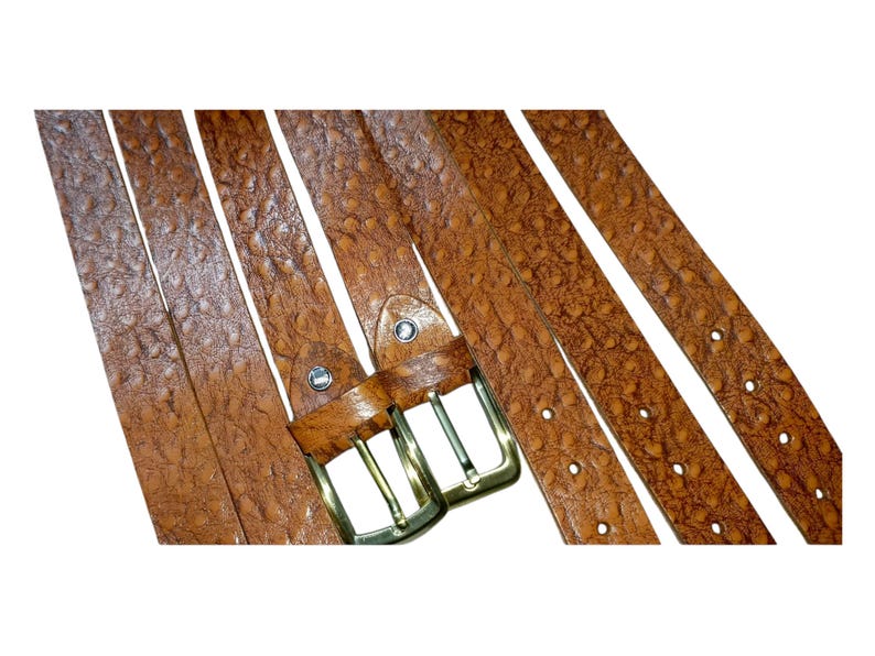 May include: Several brown leather belts with textured surfaces and brass-colored buckles are displayed against a white background. The belts have multiple holes for adjustment and a classic design.