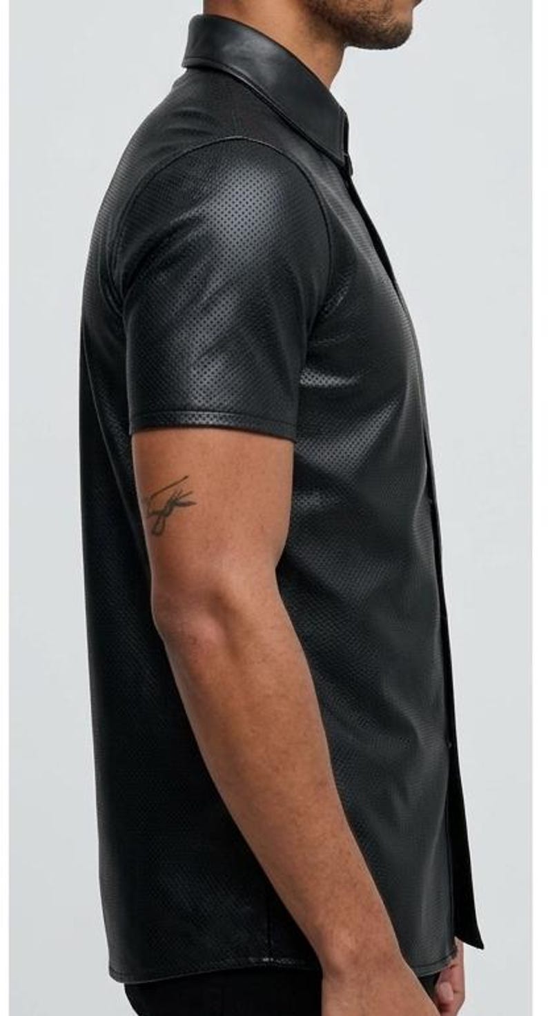 Peut inclure: Chemise noire &agrave; manches courtes avec une texture perfor&eacute;e. La chemise a un col classique et une fermeture boutonn&eacute;e sur le devant. Le tissu semble &ecirc;tre du cuir ou une mati&egrave;re semblable au cuir. La chemise est de couleur noire unie.