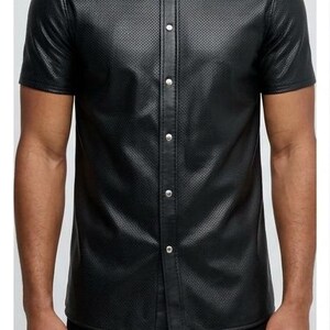 Peut inclure: Chemise noire &agrave; manches courtes avec boutons. Le tissu est textur&eacute; et la chemise a un col classique et des boutons argent&eacute;s. La chemise est de couleur noire unie.