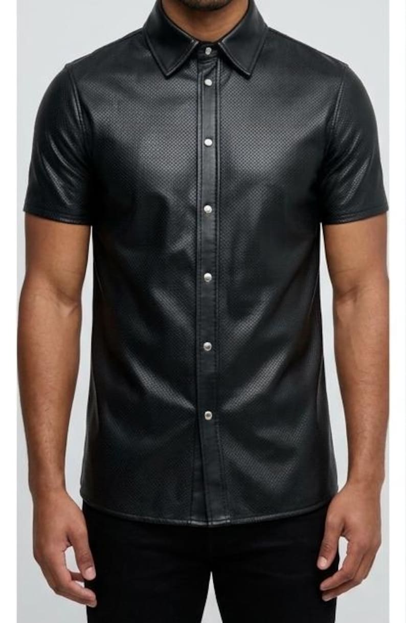 Peut inclure: Chemise noire &agrave; manches courtes avec boutons. Le tissu est textur&eacute; et la chemise a un col classique et des boutons argent&eacute;s. La chemise est de couleur noire unie.