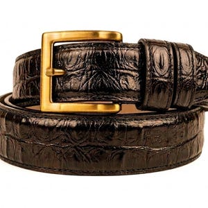 Puede incluir: Un cinturón de cuero negro con una hebilla rectangular dorada. El cinturón tiene un patrón texturizado y en relieve. La hebilla es de diseño simple y clásico. Es probable que el cinturón sea de cuero genuino.
