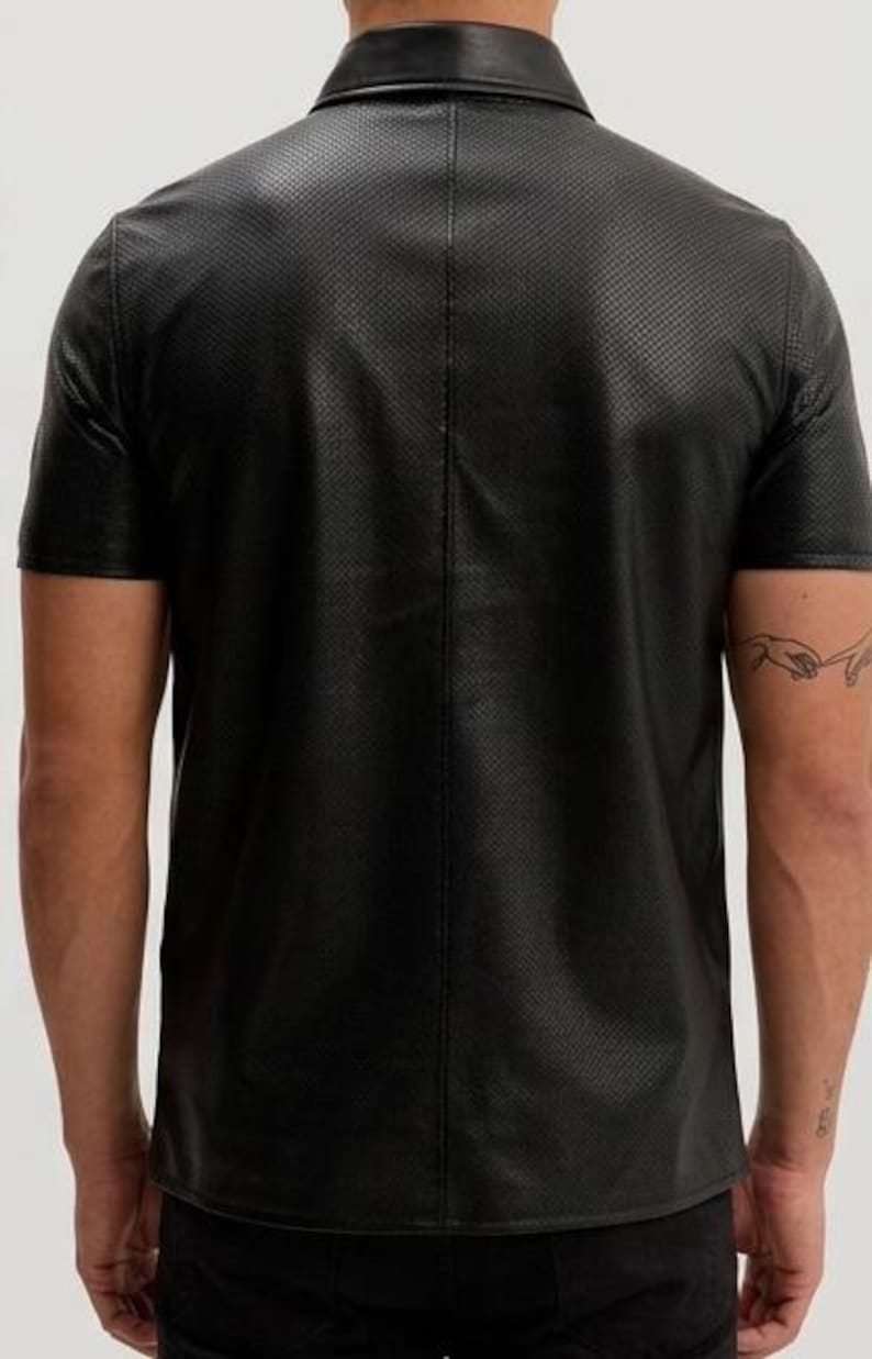Peut inclure: Chemise noire &agrave; manches courtes avec col et motif perfor&eacute; textur&eacute;. La chemise a un design polo classique et est faite d'un mat&eacute;riau semblable au cuir. Vue arri&egrave;re de la chemise.