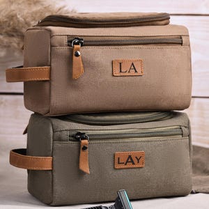 May include: A set of three ceramic mugs with a speckled, matte finish. The mugs are in shades of cream, light gray, and dark gray. Each mug has a simple, minimalist design and a rounded handle.