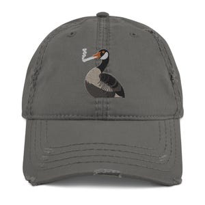 May include: Distressed gray baseball cap featuring an embroidered illustration of a smoking duck. The duck is depicted with a black head, orange beak, and a body with gray and white details. The cap has a curved brim and a worn appearance.