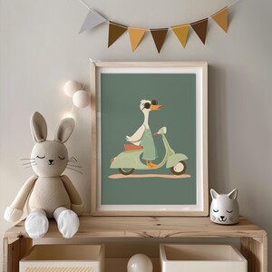 Puede incluir: Una impresi&oacute;n art&iacute;stica enmarcada que presenta un ganso con gafas de sol y un mono, montando una scooter verde menta. La obra de arte tiene un fondo verde y se exhibe en una estanter&iacute;a de madera con un conejito de peluche y una figura de gato. Una pancarta de banderas triangulares cuelga encima.