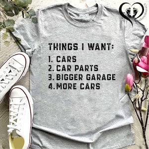 Puede incluir: Camiseta gris con el texto "THINGS I WANT: 1. CARS 2. CAR PARTS 3. BIGGER GARAGE 4. MORE CARS" impreso en negro.