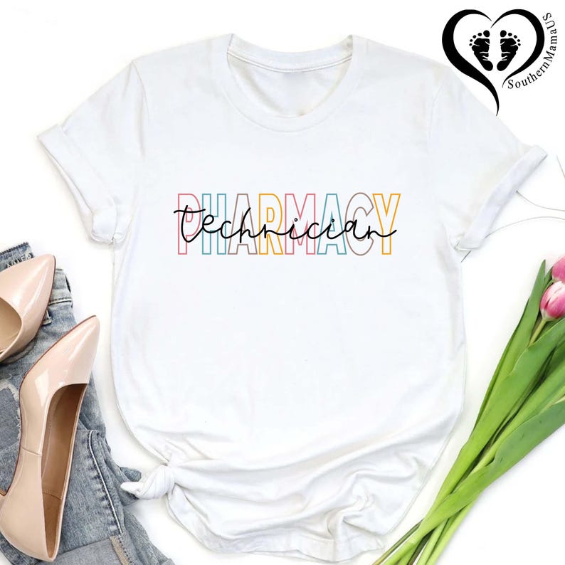 K&ouml;nnte beinhalten: Wei&szlig;es T-Shirt mit der Aufschrift "PHARMACY Technician" in bunten Blockbuchstaben und Schreibschrift. Das Shirt ist am Saum geknotet. Beige Pumps und Jeans sind links zu sehen.