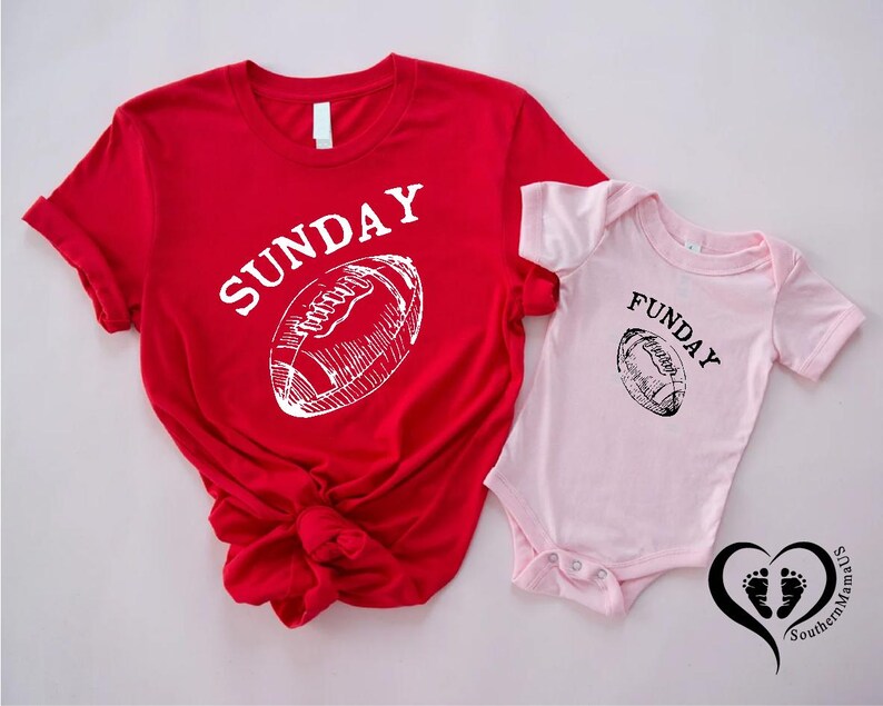 Puede incluir: Una camiseta roja con la palabra "SUNDAY" y un gr&aacute;fico de f&uacute;tbol americano blanco. Junto a ella, un body rosa para beb&eacute; con la palabra "FUNDAY" y un gr&aacute;fico de f&uacute;tbol americano negro. La imagen incluye un coraz&oacute;n con huellas.