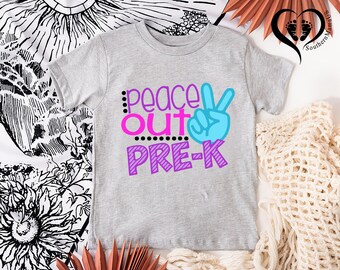 Puede incluir: Una camiseta gris claro con las palabras "peace out PRE-K" en rosa, azul y morado. El diseño incluye un signo de la paz y puntos. La camiseta es una prenda de vestir para niños.