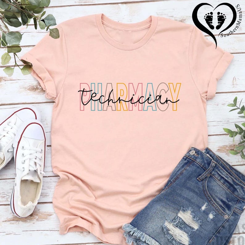 K&ouml;nnte beinhalten: Hellrosa T-Shirt mit dem bunten Schriftzug "Pharmacy Technician". Kombiniert mit Jeansshorts und wei&szlig;en Turnschuhen, ergibt sich ein l&auml;ssiger Look. Die &Auml;rmel des T-Shirts sind hochgekrempelt.