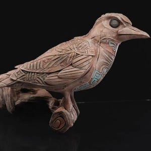 May include: A detailed, intricately carved wooden bird sculpture with a light brown finish. The bird is perched on a branch and has a stylized design with geometric patterns.