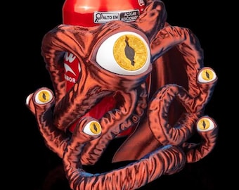 May include: A red and black 3D printed can holder shaped like a tentacled creature with multiple eyes. The holder is holding a red can of soda with the text "ACUCAR ADICIONADO" and "ALTO EM" on the side.