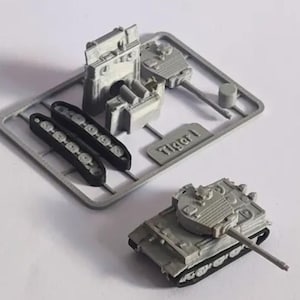 Könnte beinhalten: Grauer Kunststoff-Modellbausatz eines Tiger I-Panzers. Der Bausatz enthält verschiedene Komponenten wie den Panzerkörper, den Turm, die Ketten und andere Teile. Der Text "Tiger I" ist auf dem Gussrahmen sichtbar.