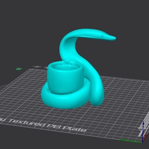 May include: A 3D-rendered, turquoise snake-shaped object with a cylindrical cup. The snake's head is raised, and its body coils around the cup. The object is on a grid-patterned surface.