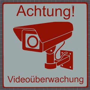 Könnte beinhalten: Ein quadratisches Schild mit hellgrauem Hintergrund und rotem Rand. Das Schild zeigt eine rote Grafik einer Überwachungskamera sowie den roten Text "Achtung!" oben und "Videoüberwachung" unten, was auf eine Videoüberwachung hinweist.