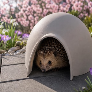 May include: A hedgehog peeks out from a light gray, dome-shaped shelter. The shelter is on a gray stone patio, surrounded by spring flowers, including purple crocuses and white snowdrops. The hedgehog has brown and tan quills.