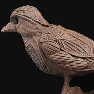 May include: A detailed wooden sculpture of a bird with intricate carvings and a textured surface. The bird is perched on a branch.