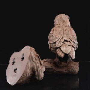 May include: A detailed ceramic sculpture of an owl perched on a branch. The owl is brown and has intricate details on its feathers. The sculpture is a great addition to any home decor.
