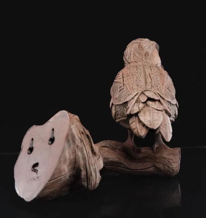 May include: A detailed ceramic sculpture of an owl perched on a branch. The owl is brown and has intricate details on its feathers. The sculpture is a great addition to any home decor.