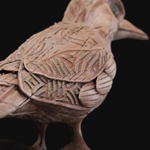 May include: A detailed clay sculpture of a bird with intricate patterns and textures. The bird is brown and has a long beak. The sculpture is a unique and artistic piece.