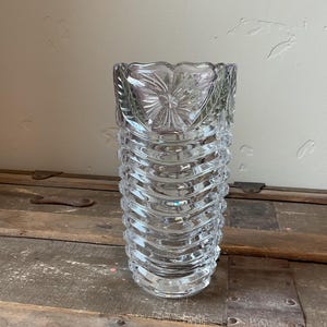 May include: A clear glass vase with a textured, ribbed design and a floral pattern around the top.